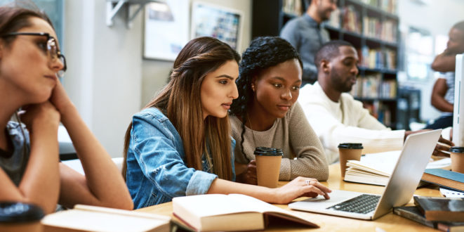 Shot of two young women using a laptop together in a college library